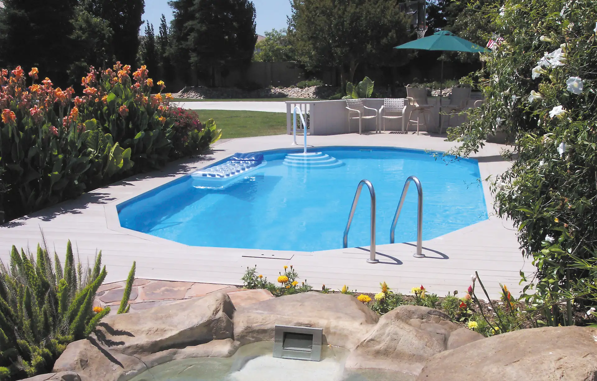 An oval Doughboy Pool is fully recessed in the ground and surrounded by an elegant pool surround. Doughboy's above-ground pools are unique in that they are strong enough for a fully-recessed pool installation.