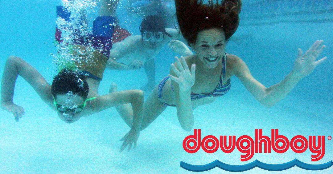 Kids waving to the camera from under water in a swimming pool